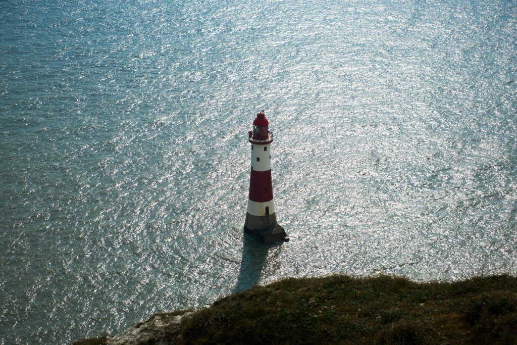 Aerial view of Beachy Head Lighthouse against sparkling sea waters in Eastbourne, England.